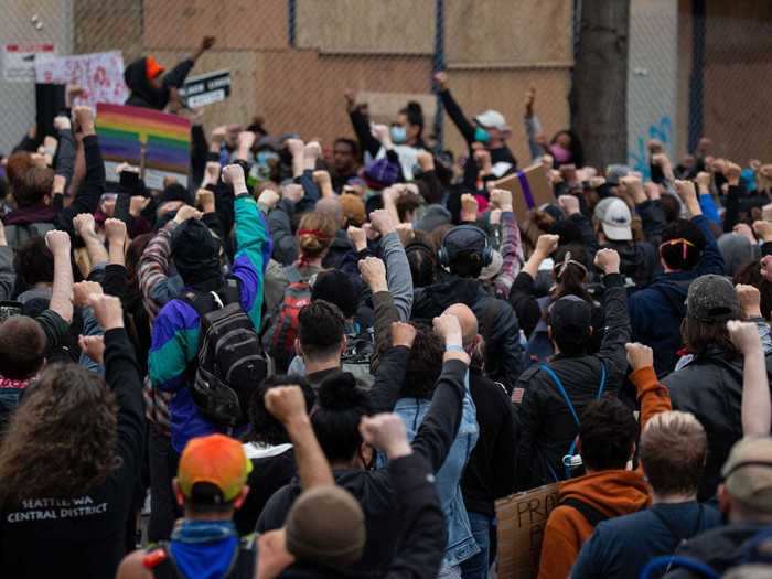 In Seattle, Washington, demonstrators are seen raising their fists together outside of a police precinct.