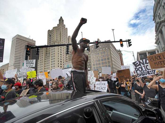 In Providence, Rhode Island, a man is captured standing outside of his car with his fist raised in solidarity with protesters.