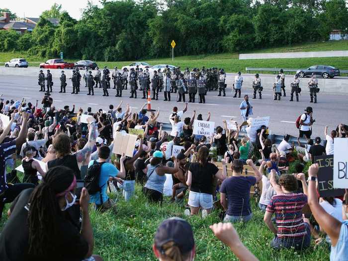 In St. Charles, Missouri, protesters are seen taking a knee while police line up across from them in the road.