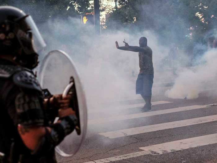 In Atlanta, Georgia, a protester holds his hands up as police spray him with tear gas.