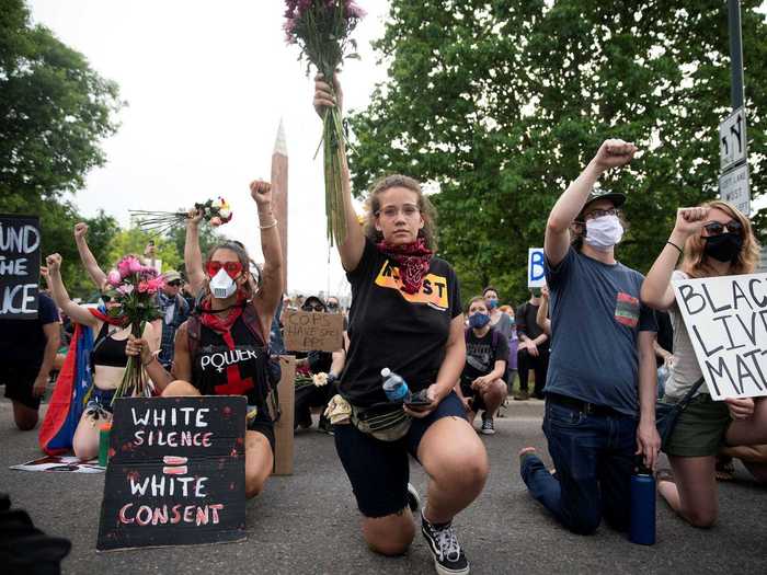 In Denver, Colorado, protesters are seen holding signs and flowers in the air while taking a knee.