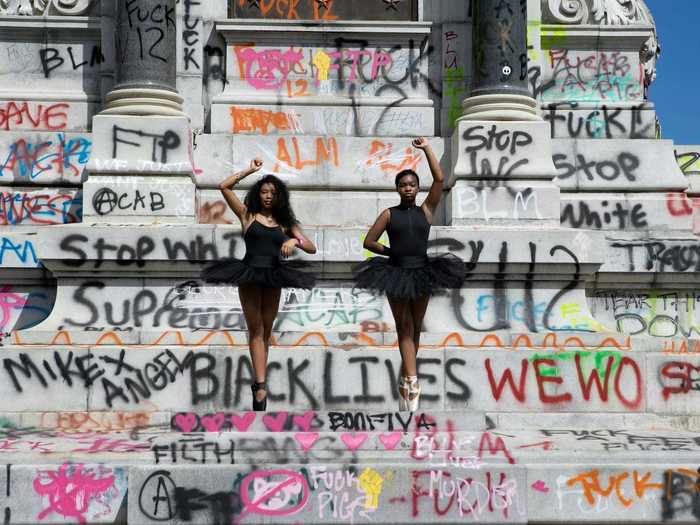 In this photo, two young ballerinas pose in front of a Robert E. Lee statue after protesters completely reclaimed the monument with written messages.