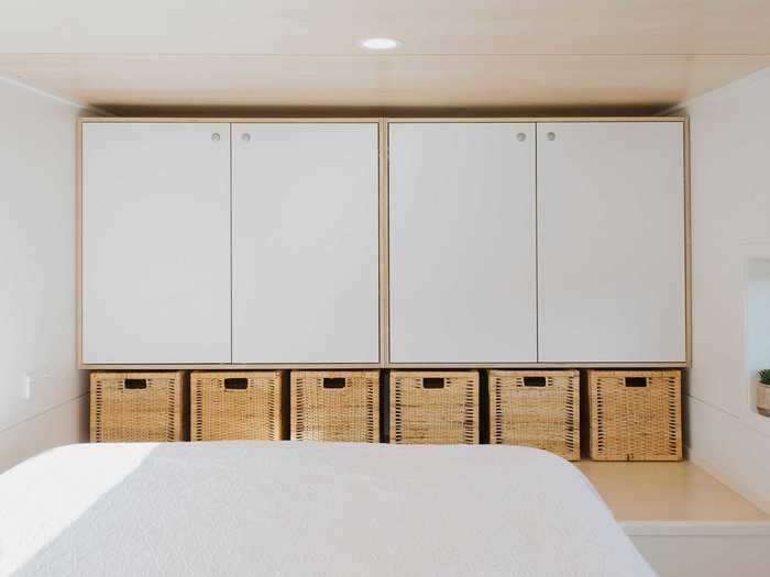 Across the bed is a series of cupboards and storage baskets that take the place of a traditional closet.