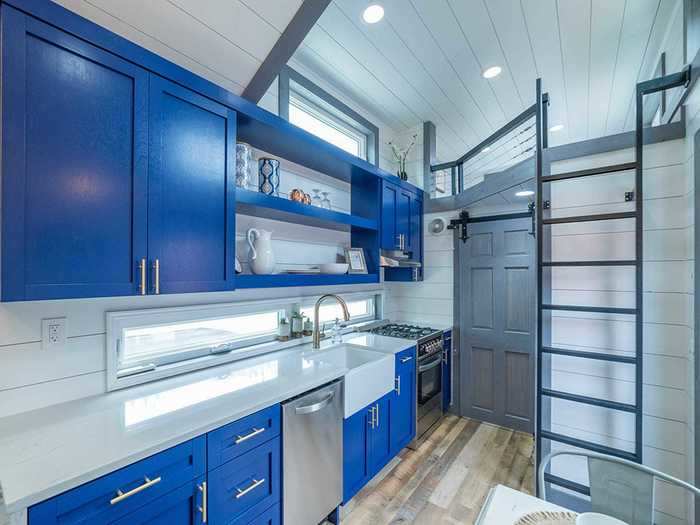 The kitchen is adorned with blue cabinets that are contrasted by the long quartz countertop.