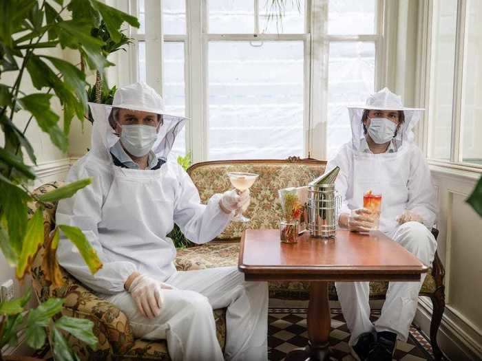 Bartenders don beekeeper suits that function as PPE at a bar in London, England.