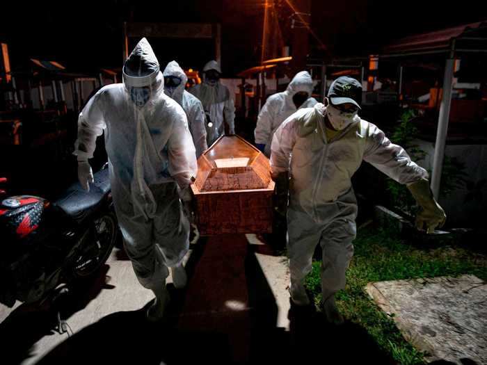 In this photo, gravediggers in personal protective gear are seen carrying the body of someone who died from the virus on Marajo Island.