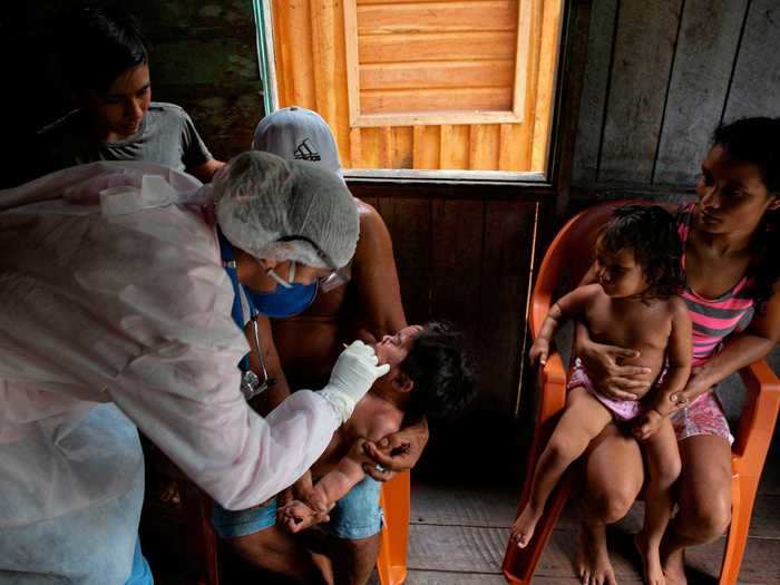 And in this photo, a healthcare worker dressed in full personal protective equipment is seen checking the health of a baby.