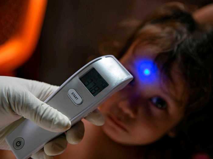 In this photo, a healthcare worker is seen taking the temperature of a small child.