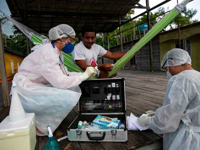 Healthcare workers arrive with a full case of medical supplies, including thermometers and coronavirus testing kits.