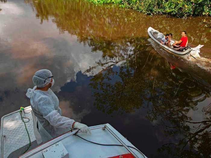 Here, a healthcare worker is seen riding in a boat alongside two passengers on Marajo Island.