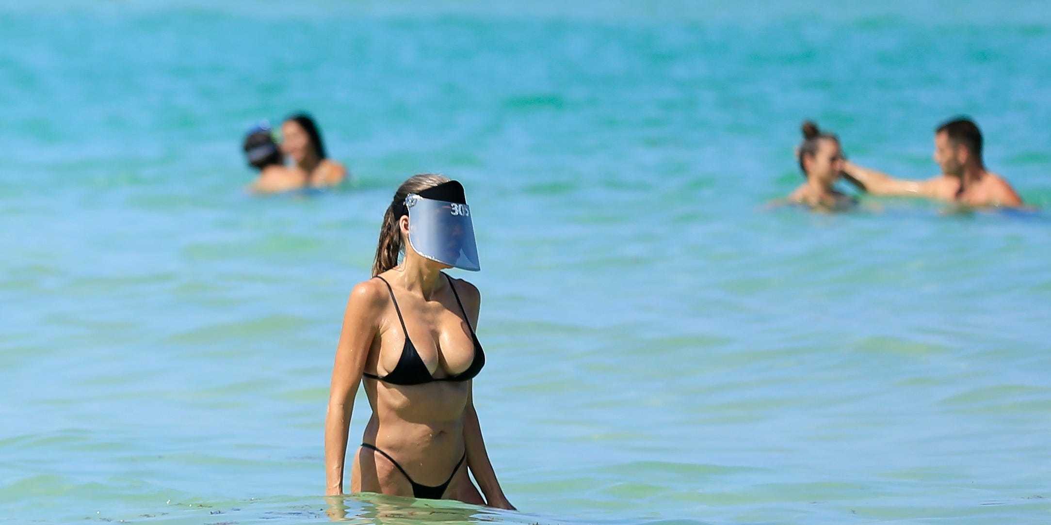 MIAMI BEACH, FLORIDA - JUNE 10: A woman wears a face shield as she wades in the ocean off South Beach on June 10, 2020 in Miami Beach, Florida. Miami-Dade county and the City of Miami opened their beaches today as the area eases restrictions put in place to contain COVID-19. (Photo by Cliff Hawkins/Getty Images)