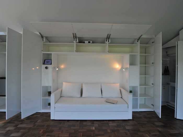 For example, the couch folds out into a bed, and is surrounded by built-in storage shelves.