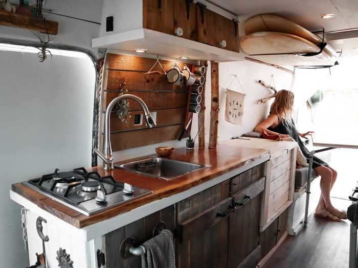 The van has a kitchen that features running water, a stove, and a refrigerator.