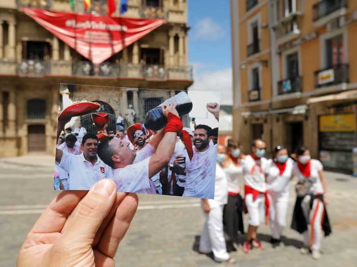 To commemorate the event, Reuters photographer Jon Nazca held up past photographs in their locations to show what the festival would typically look like. Here, a man is seen drinking wine from a large bottle before the opening ceremony.