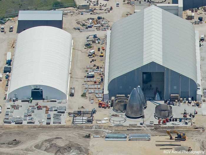 Different tents house different phases of construction. In the gray "onion" tent to the right, new and ever-better-looking rocket nosecones roll out of the bay doors.