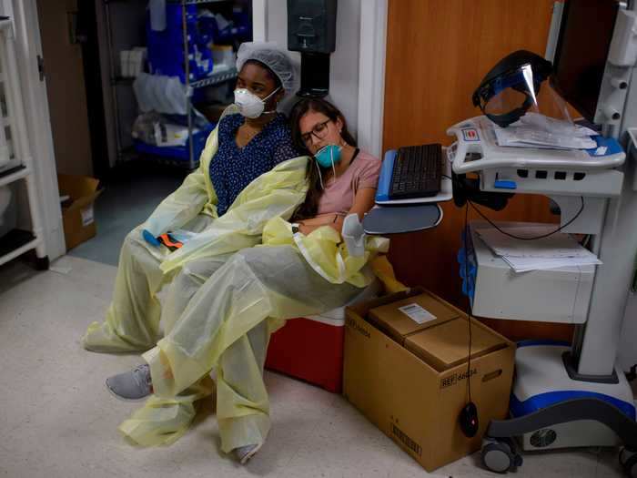 Here, a tired healthcare worker is seen resting against a colleague outside of the coronavirus unit.