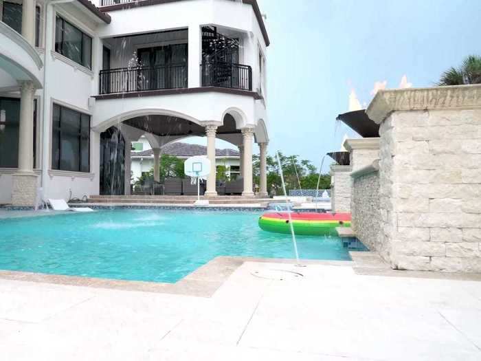 The large pool has sprinklers, beach chairs, and even a basketball hoop.