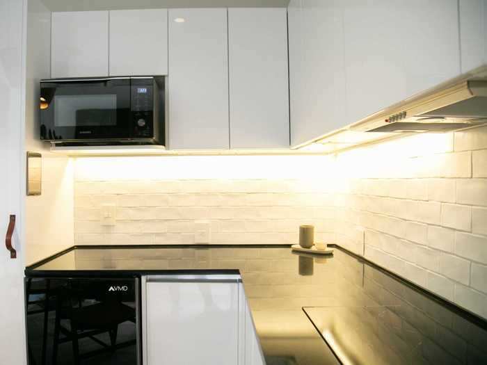 The kitchen is modern-looking, with white no hardware cabinets and black appliances.