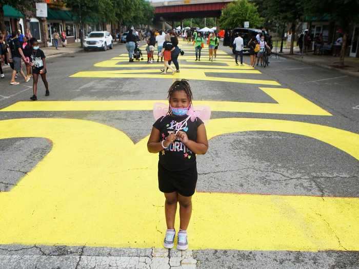 Here, a young girl is seen standing in front of the Tulsa mural to commemorate Juneteenth, the anniversary of Texas freeing slaves in in 1865.