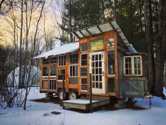 This tiny home lined with windows on a farm in the Catskills makes sure guests can still enjoy the outdoors while curling up inside on a day bed lined with woven rugs.