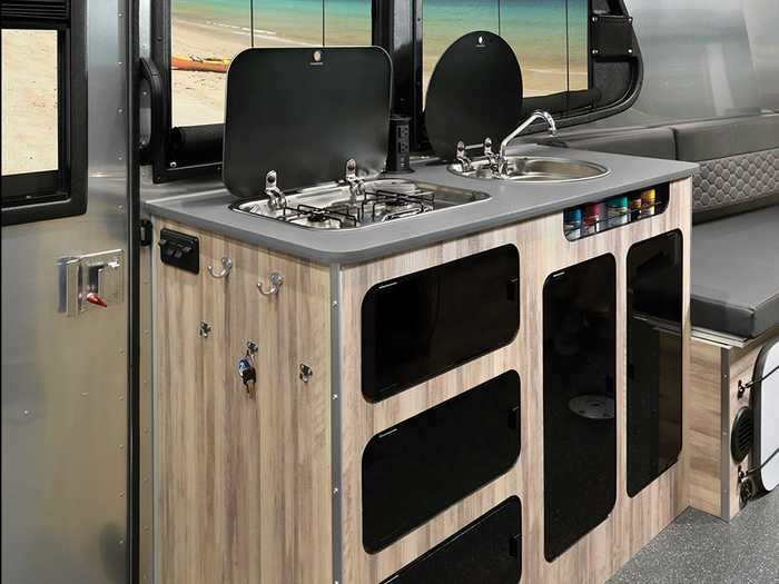 The galley — which sits between the bed and dinette — consists of a countertop, cabinets, sink, and dual-burner cooktop. The refrigerator and optional microwave are across the way next to the dinette.