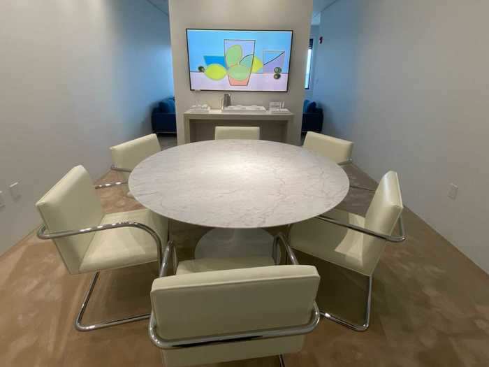 The room has everything a team of businesspeople will need to hold a meeting including a large screen to display presentations,