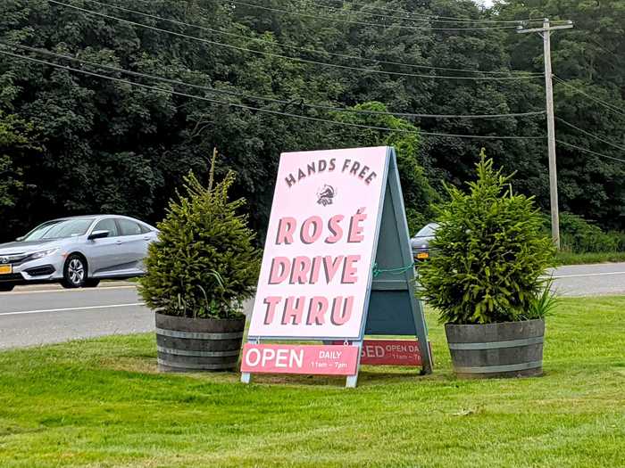 A bright-pink sign on the side of the road attracts passersby who want to pick up some rosé to enjoy later at home.