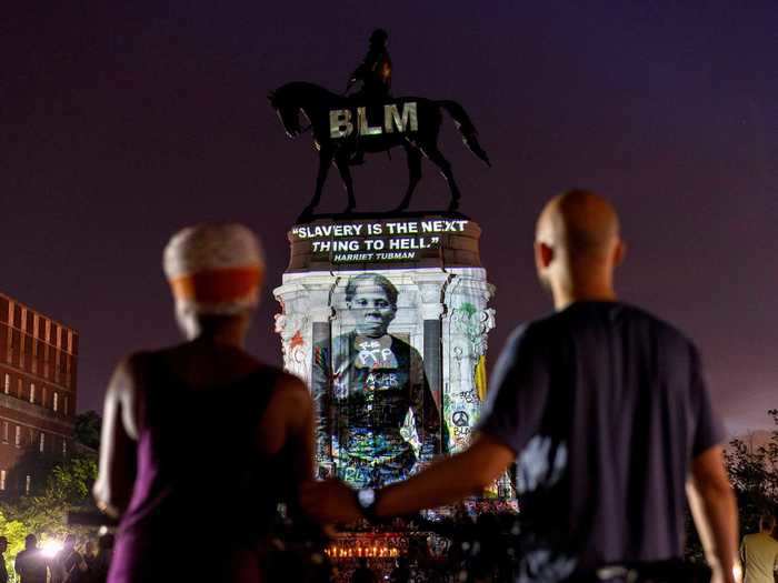 In this photo, people are seen gathering around to see the projection of Tubman. The quote above her image reads, "Slavery is the next thing to hell."