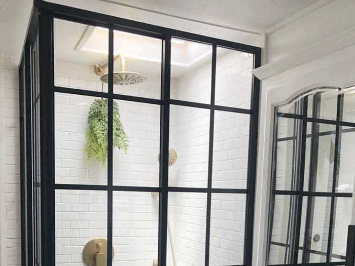 The new shower has subway tile and glass doors.