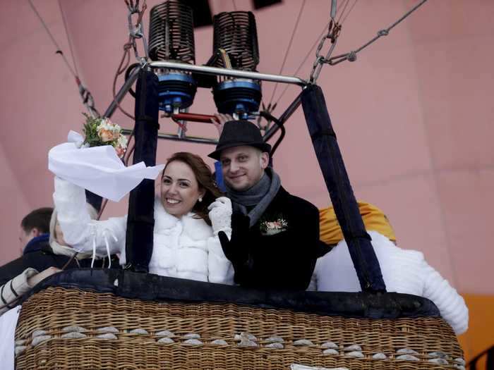 During the festival in Latvia, each hot-air balloon was tied to a car to prevent it from soaring too high.