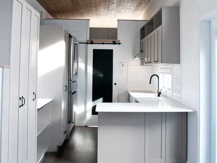 The kitchen has quartz countertops and a white tile backsplash, contrasting the darker grey cabinets.