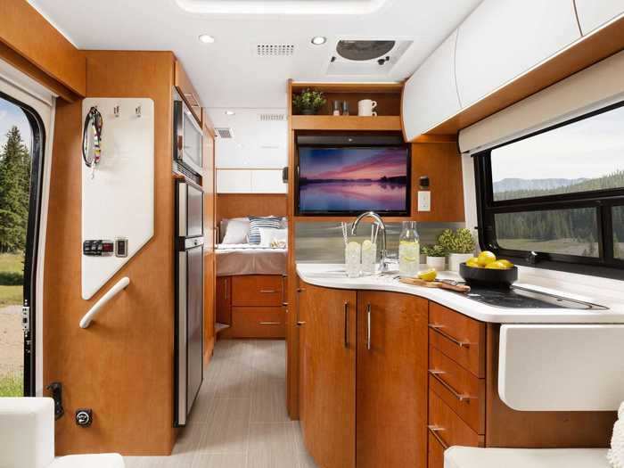 The layout also includes details like a pass-through storage compartment that has both interior and exterior access, and a chaise lounge by the front of the RV that can also be used as the dining area.