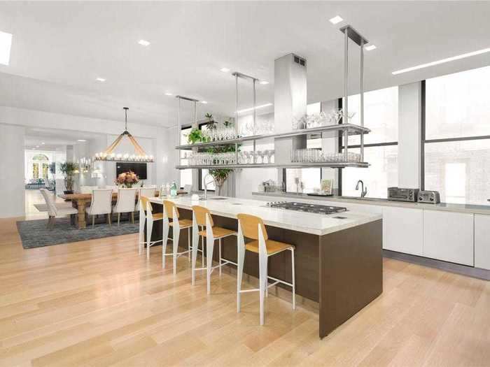 The kitchen features an island with a seating area, as well as a large dining table.