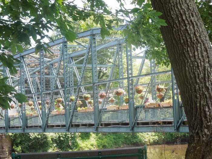 The Old Drake Hill Flower Bridge over the Farmington River is lined with potted flowers on both sides.