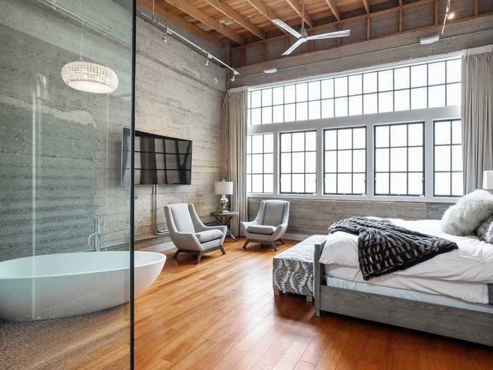 Warehouse-style windows flood the upper level bedroom with light.