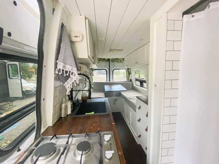 The van also features a kitchen, complete with a faucet, a stovetop, and a refrigerator.