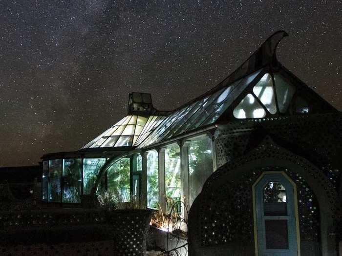 At night, the Phoenix Earthship is illuminated, and the surrounding desert showcases a starry night sky.