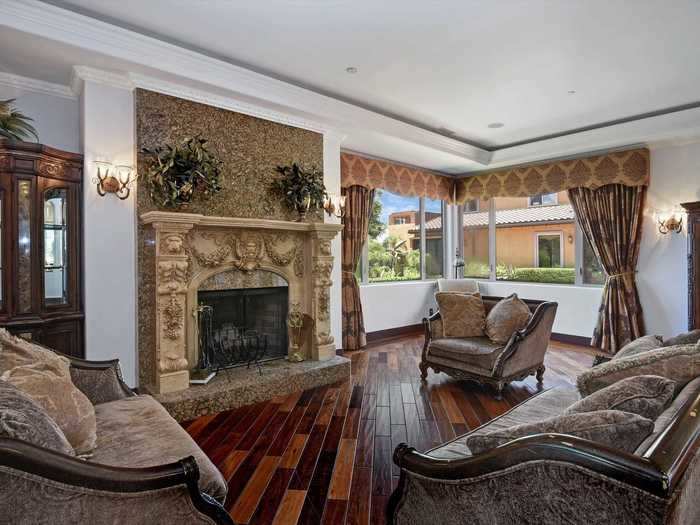 The formal living room is the central gathering space and features a carved marble-granite fireplace as its centerpiece.