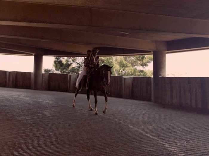 The couple leaves on horseback, riding through a parking garage.