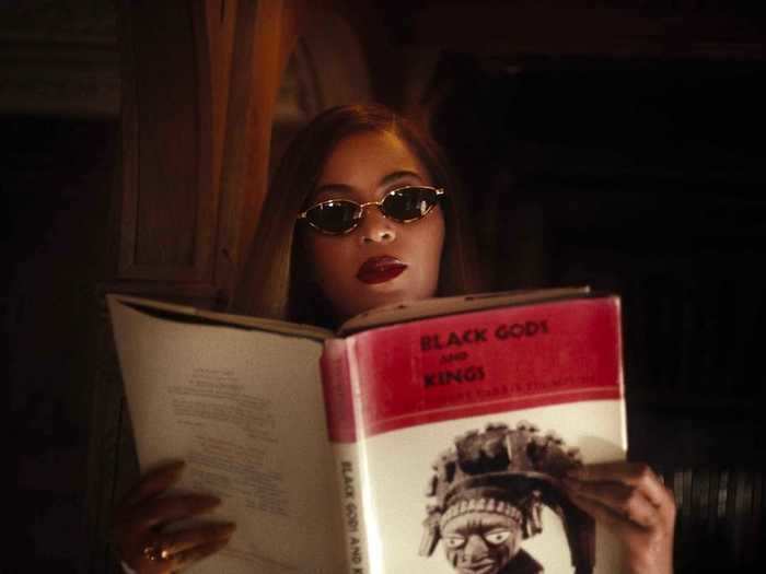 Beyoncé cracks open a book titled "Black Gods and Kings."