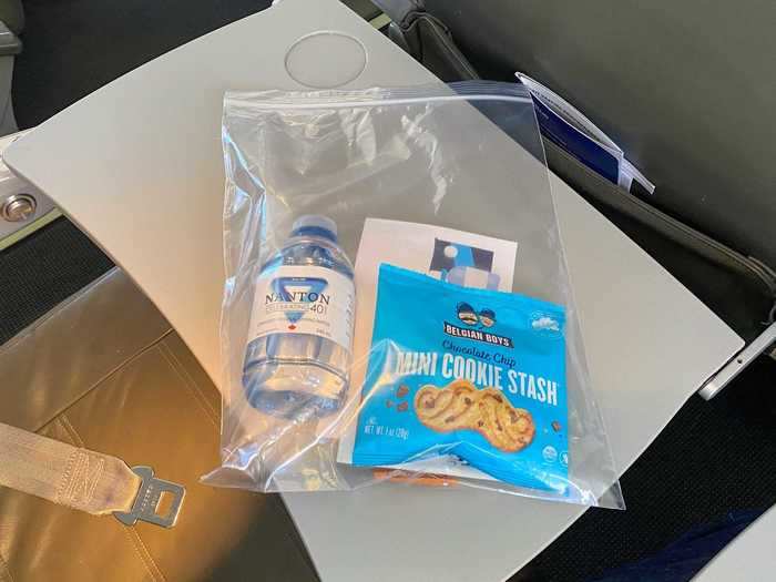 One flight attendant distributed sealed plastic bags with a drink, snacks, and napkins.