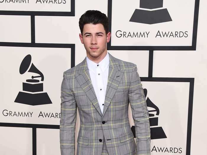 Nick attended the 2015 Grammys without his siblings, wearing a buttoned up white shirt and a gray striped suit.