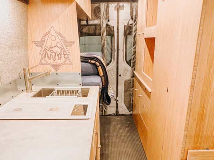 The van has a kitchen, living space, and a bedroom in the back.