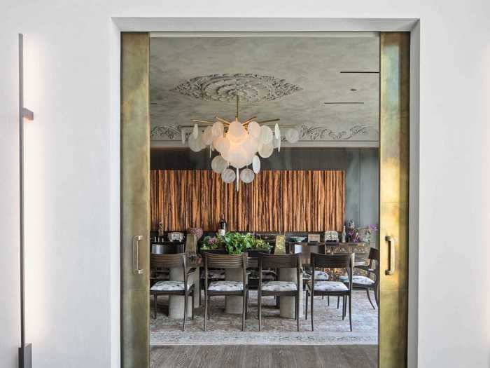 A formal dining room is anchored by a large chandelier.