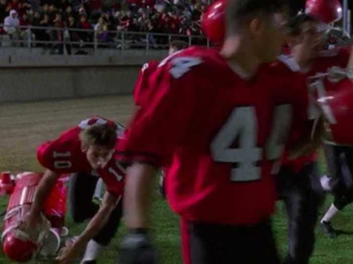 A football player knocks over a cooler, but it