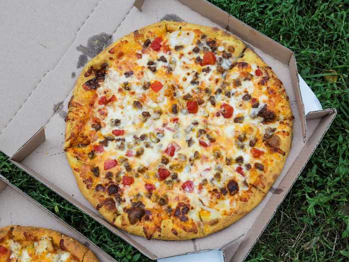 The cheeseburger pizza is made with ground beef, onions, tomatoes, provolone, cheddar, and American cheese on ketchup and mustard sauce.