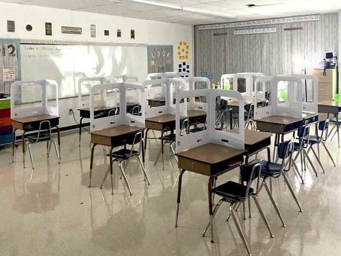 Each desk in her classroom has a shield to help separate her students.