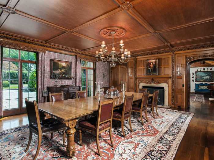 A formal dining room with wood-paneled walls and ceiling can seat at least 10 people.