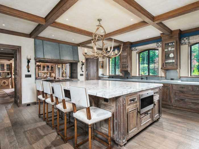 The kitchen features a massive center island and an antler chandelier.