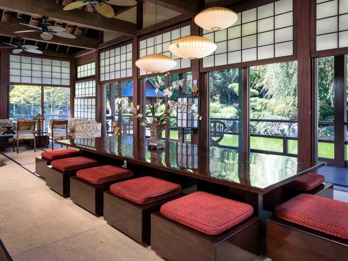 The teahouse features a long table surrounded by low-lying red-and-black seats ...